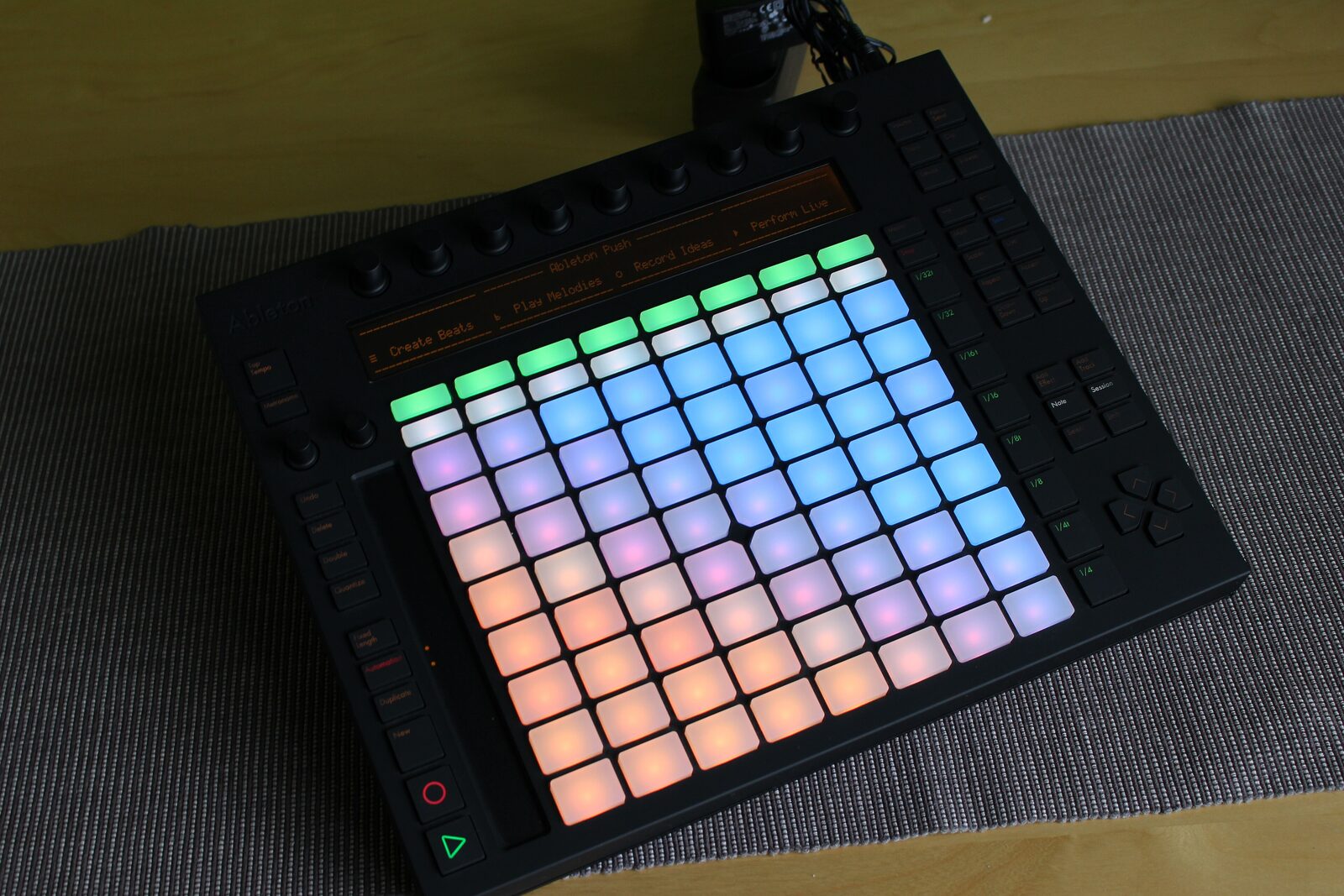 An Ableton Push pad controller with its colour-lit 8 by 8 grid of pads and the words Ableton Push on its display