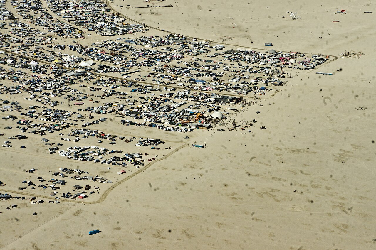 Aerial view of Black Rock City from above, showing the desert playa surrounding the temporary settlement. Photo by Peretz Partensky, CC BY 2.0, via Wikimedia Commons.