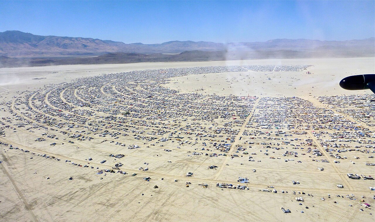 Aerial view of Black Rock City during Burning Man, showing the temporary city's radial street grid laid out on the desert playa.