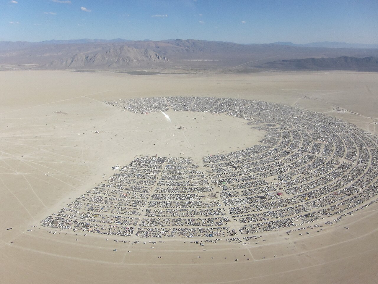 Aerial view of Black Rock City, the temporary desert metropolis built each year for Burning Man. Photo by Kyle Harmon, licensed CC BY 2.0, via Wikimedia Commons.