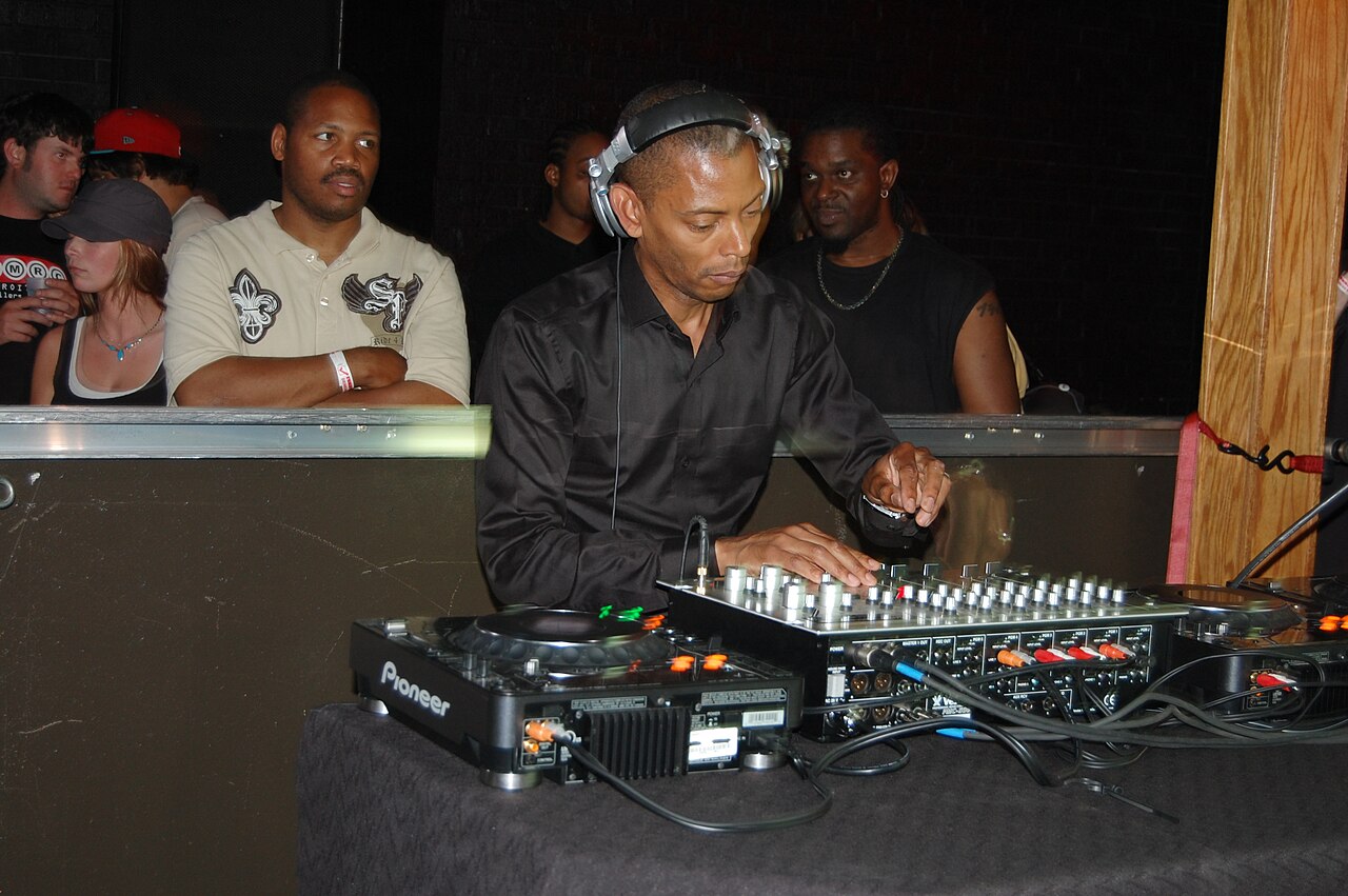 Jeff Mills wearing headphones and playing a DJ mixer at a club event in Detroit, 2010