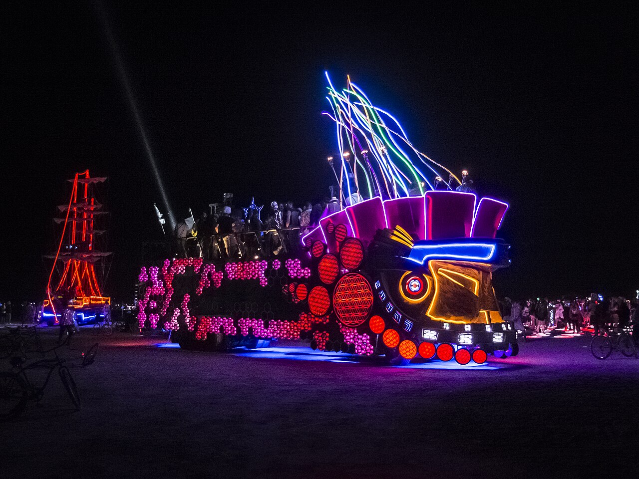 The Mayan Warrior art car lit up at night on the playa in an earlier year, before the collective paused the vehicle for 2026 in favor of the stationary Discosmos camp. Photo: Billie Grace Ward via Wikimedia Commons (CC BY 2.0).