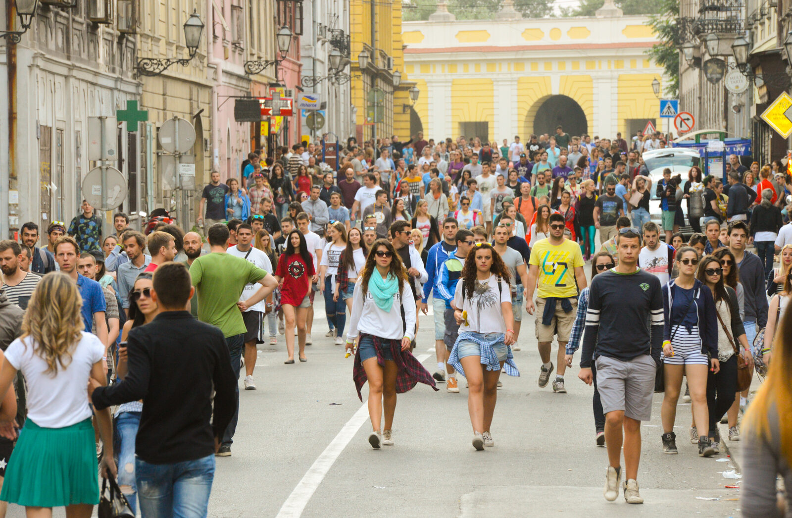A crowd of festival-goers walking down a street in Novi Sad's Petrovaradin district towards a yellow gateway during EXIT in 2015