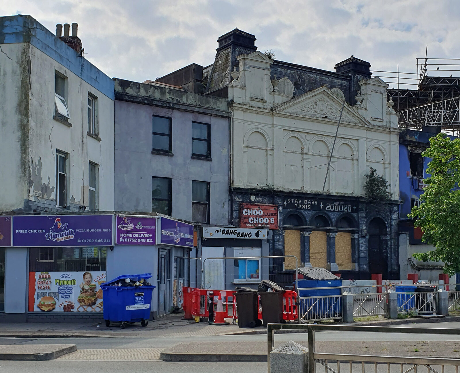 A former nightclub building in Plymouth with boarded-up doors and a faded Choo Choos sign beside a takeaway shop