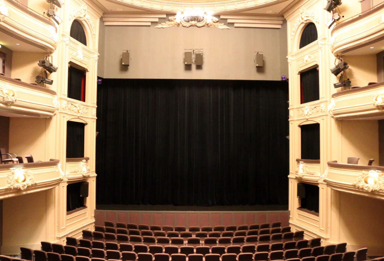 Interior of the Koninklijke Schouwburg in The Hague, one of Rewire's venues, looking from the stalls toward a black stage curtain framed by tiered balconies.